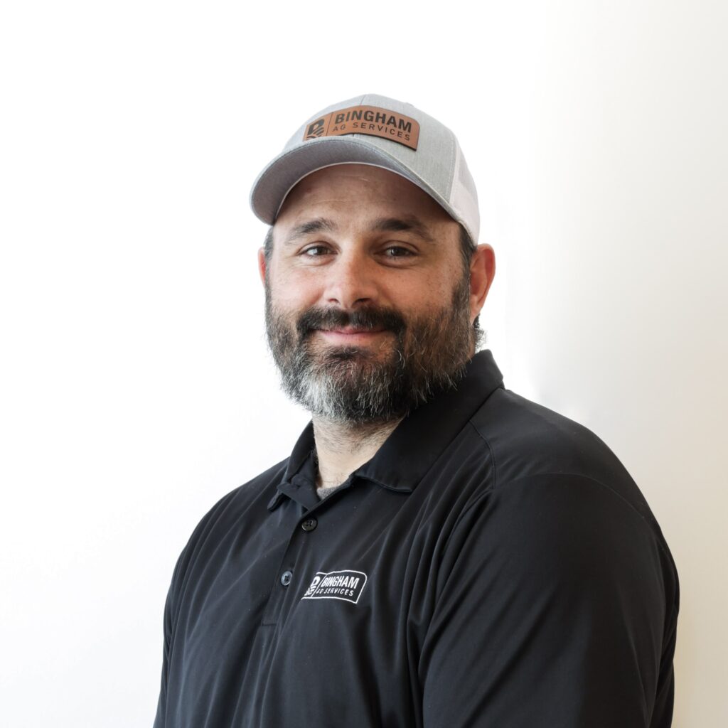 Professional headshot of Lucas Sprague, Bingham Ag Services team member, wearing a Bingham Ag Services cap and dark polo shirt